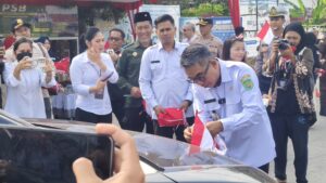 Ardiansyah Sulaiman, Bupati Kutim saat membagikan bendera merah putih pada pengendara di kawasan Simpang Tiga Pendidikan, Rabu (12/8/2026)