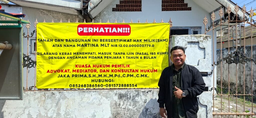 Keterangan Foto: Advokat Jaka Prima berfoto di depan rumah yang menjadi objek sengketa di Kota Mojokerto. Spanduk pemberitahuan terkait status kepemilikan bangunan terpasang di bagian depan properti tersebut. Foto: Istimewa.